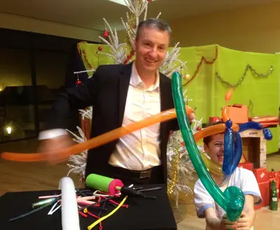 Francis sculpte un ballon devant des enfants lors d'une fête